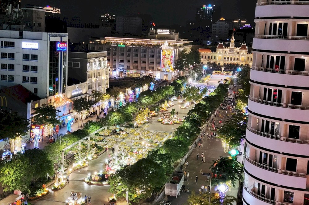 Vibrant night scene on Nguyen Hue Walking Street with sparkling lights, people strolling, and modern coffee shops lining both sides of the avenue